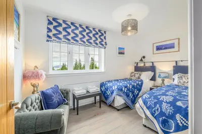 a bedroom with two beds and a couch and a window at Blà Bheinn by Birch Stays in Dunollie