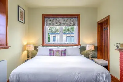 a bedroom with a large white bed with a window at Blà Bheinn by Birch Stays in Dunollie