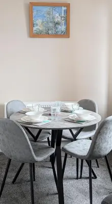 a dining room table with chairs and plates and a picture at Whisky Row in Campbeltown