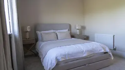 a bedroom with a bed with white sheets and pillows at Ardlui House Gardens in Hamilton