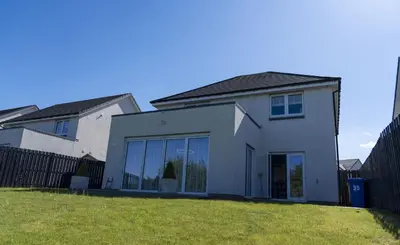 a white house with large windows and a fence at Ardlui House Gardens in Hamilton