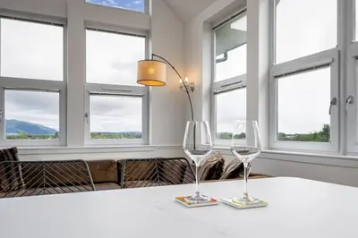 two wine glasses sitting on a table with windows at The Stirling Penthouse - Free Parking in Stirling