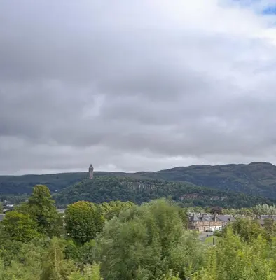 a tower on top of a hill with trees at The Stirling Penthouse - Free Parking in Stirling