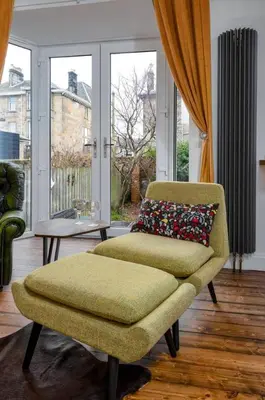 a living room with a chair and a table and windows at Tranquil Glasgow Retreat in Glasgow
