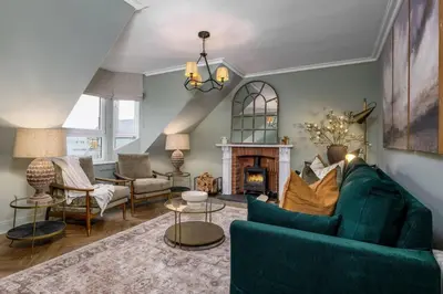 a living room with a blue couch and a fireplace at Ledi Lookout Callander in Stirling