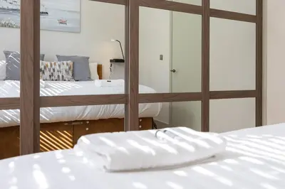 a bedroom with two beds and a mirror at Luxury Flat Near Hove Station parking sleeps 4 in Moffat