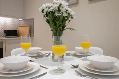 a table with a vase of flowers and two glasses of orange juice at Luxury Flat Near Hove Station parking sleeps 4 in Moffat