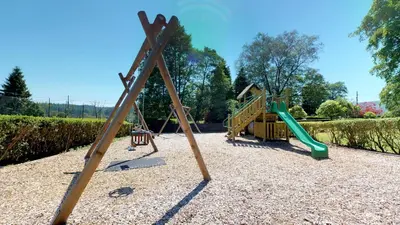 a playground with two swings and a slide at Macdonald Forest Hills Resort in Aberfoyle
