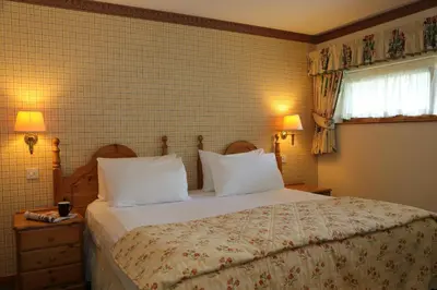 a bedroom with a large bed with white pillows at Macdonald Forest Hills Resort in Aberfoyle