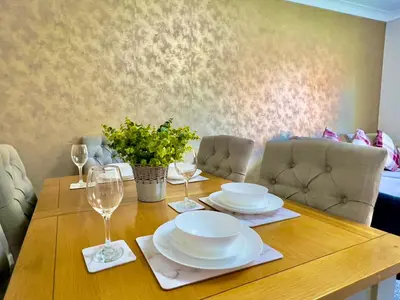 a wooden table with plates and wine glasses on it at Stylish City Apartment with Free Parking near Town in Glasgow
