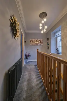 a hallway with a wooden staircase with a stair case at Stay Torrance-Village Home Near Glasgow in Glasgow