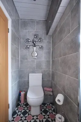 a bathroom with a toilet and a vase with flowers on the wall at Stay Torrance-Village Home Near Glasgow in Glasgow