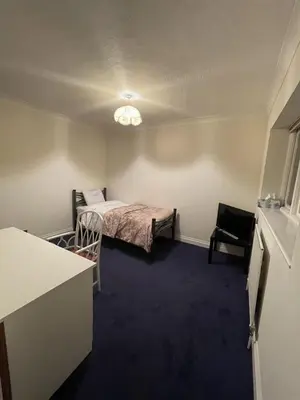 a small room with a bed and a table and chair at 14 Maple Mews in Moffat