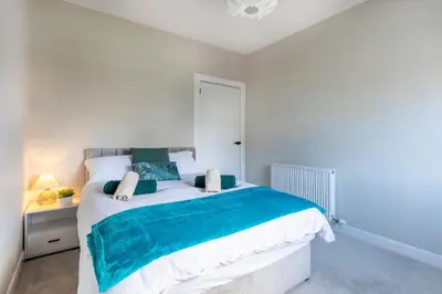a bedroom with a large bed with blue and white sheets at Modern 3 Bedroom home in Kings Park in Polmadie
