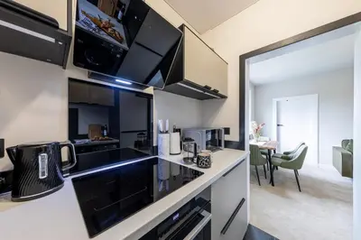 a kitchen with black appliances and a living room at Modern 3 Bedroom home in Kings Park in Polmadie