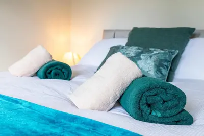 a bed with green and white towels on it at Modern 3 Bedroom home in Kings Park in Polmadie