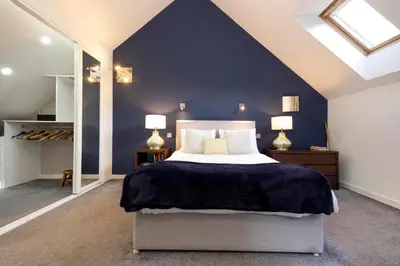a bedroom with a large bed with a blue wall at Chic Edinburgh 3-Bedroom 2-Storey House near City Centre with Free Parking in Edinburgh