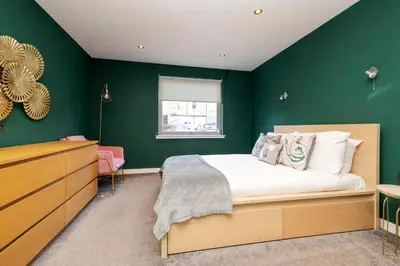 a bedroom with green walls and a bed and a dresser at Chic Edinburgh 3-Bedroom 2-Storey House near City Centre with Free Parking in Edinburgh