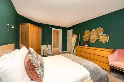 a bedroom with green walls and a bed and a chair at Chic Edinburgh 3-Bedroom 2-Storey House near City Centre with Free Parking in Edinburgh