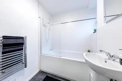 a white bathroom with a tub and a sink at Cosy 3 bed flat in Kings Park in Glasgow