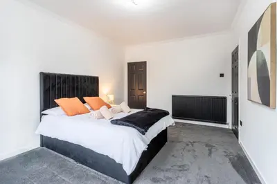 a bedroom with a large bed with orange pillows at Cosy 3 bed flat in Kings Park in Glasgow