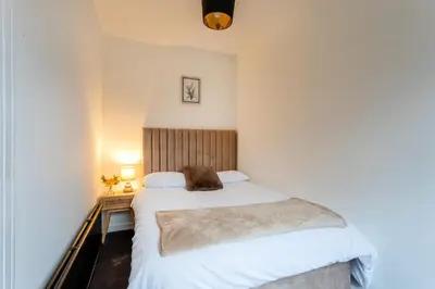 a small bedroom with a bed and a desk at Cosy 3 bed flat in Kings Park in Glasgow