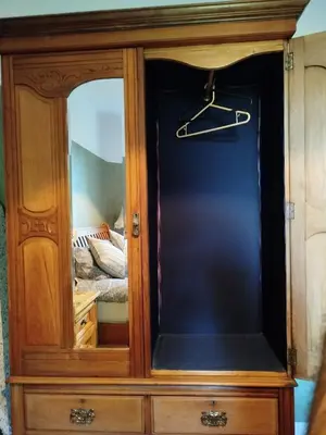a wooden cabinet with a mirror in a bedroom at Lovely place at Stenhouse in Edinburgh