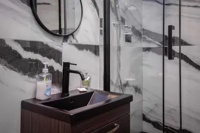 a bathroom with a sink and a shower with a mirror at Stylish Edinburgh Apartment in Edinburgh