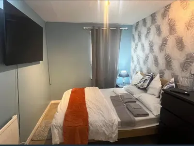 a small bedroom with a bed with an orange and white blanket at Stylish 3 bedroom house in Glasgow