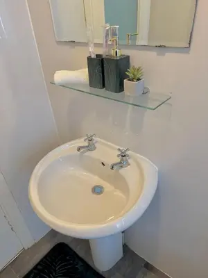 a white bathroom with a sink and a mirror at Comfort in the East in Glasgow