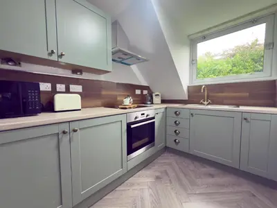 a kitchen with white cabinets and a window at Upstairs at Carlingford in Newton Mearns
