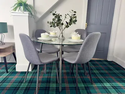 a dining room with a glass table and chairs at Upstairs at Carlingford in Newton Mearns