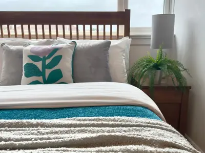 a bedroom with a bed with pillows and a plant at Upstairs at Carlingford in Newton Mearns