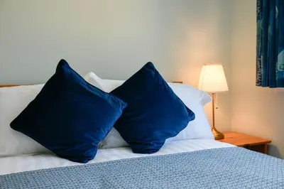 a bed with two blue pillows on top of it at Stunning Coastal Home - Garden, Views, Pet Friendly in Connel