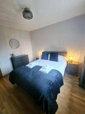 a bedroom with a large bed with blue sheets and pillows at Stunning Coastal Home - Garden, Views, Pet Friendly in Connel