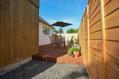 a wooden deck with a chair and an umbrella at Stunning Coastal Home - Garden, Views, Pet Friendly in Connel