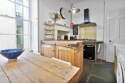 a large kitchen with a wooden table and a clock at Charming Central Stay in Moffat