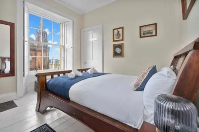 a bedroom with a large bed and a window at Charming Central Stay in Moffat
