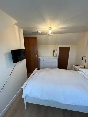 a bedroom with a white bed and a flat screen tv at Tigh-Na-Croit in Whitehouse