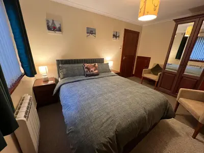 a bedroom with a bed and a chair at The Cottage at Craigavon House in Ballachulish