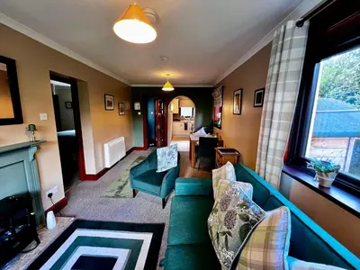 a living room with a green couch and a window at The Cottage at Craigavon House in Ballachulish