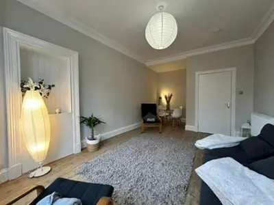 a living room with a blue couch and a rug at Appin Apartments - Welcome to a delightful and cozy one bedroom flat in Glasgow