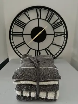 a clock and a pile of towels on a table at Appin Apartments - Welcome to a delightful and cozy one bedroom flat in Glasgow