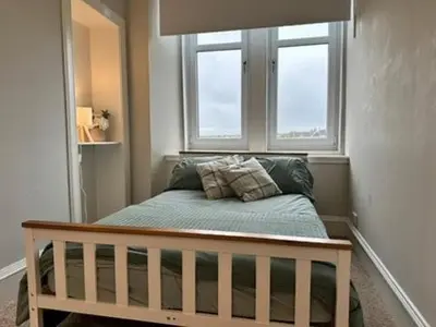 a bed in a room with two windows at Appin Apartments - Welcome to a delightful and cozy one bedroom flat in Glasgow