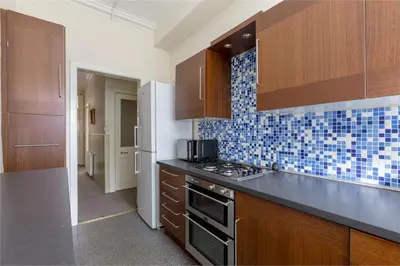 a kitchen with wooden cabinets and a stove top oven at 3 Bedrooms Flat in Central Edinburgh New Town , Lothian Road in Edinburgh