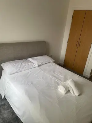 a white bed with two white towels on it at Maison 109 Suite - Modern City Apartment in Glasgow