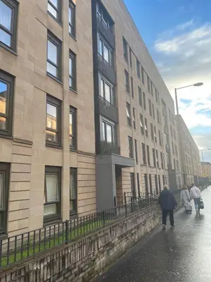 a person walking down a street next to a building at Maison 109 Suite - Modern City Apartment in Glasgow