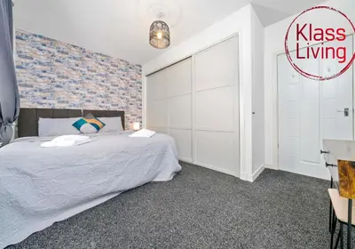 a bedroom with a king sized bed and a brick wall at Lady Wilson Apartment by Klass Living Airdrie in Airdrie