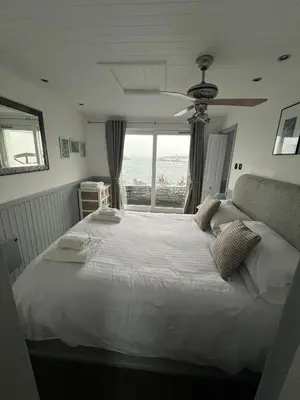 a bedroom with a large white bed and a window at Misty Isles Cottage- Ellenabeich, Easdale, Isle of Seil