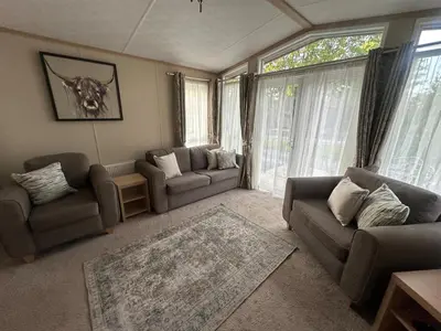 a living room with couches and a large window at Glen-coo in Auchterarder